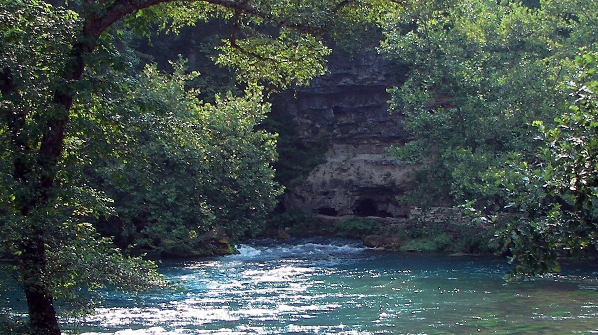 Big Spring in the Missouri Ozarks flowing from a wooded limestone bluff